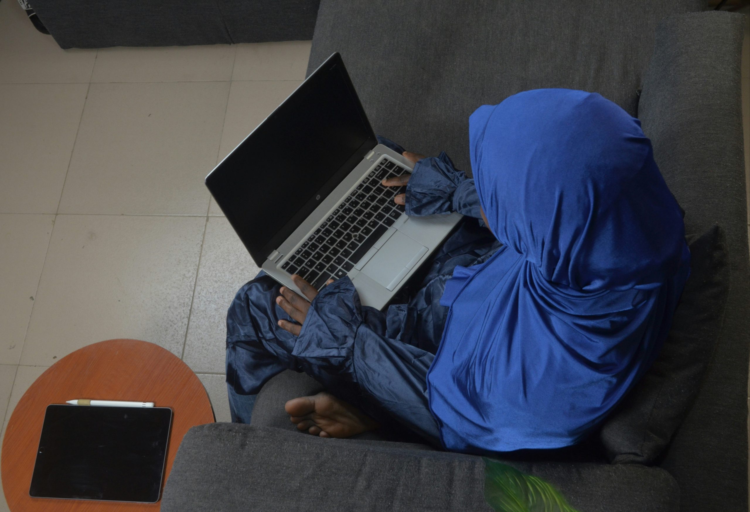 Bird’s eye view of woman on couch with laptop technology-facilitated gender-based violence