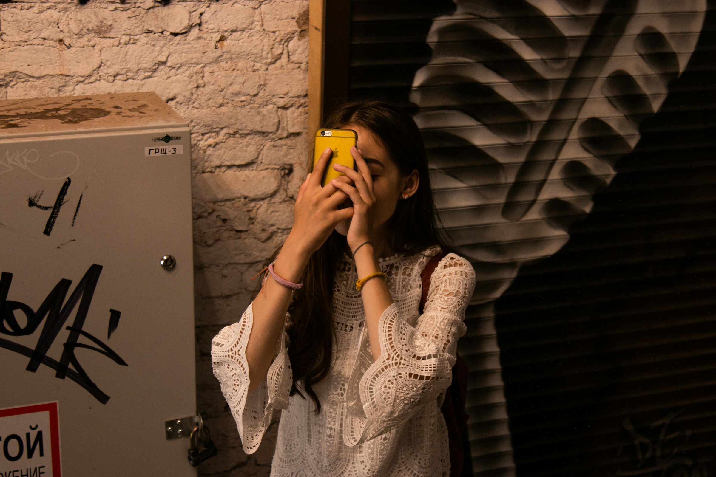 Woman covering face with phone Technology-facilitated gender-based violence